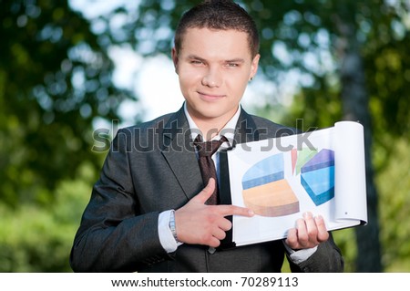 Young business man show graph on outdoor meeting, at green park. Student.