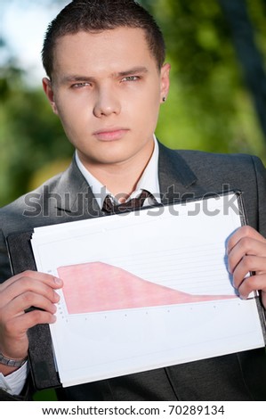 Young business man show graph on outdoor meeting, at green park. Student.