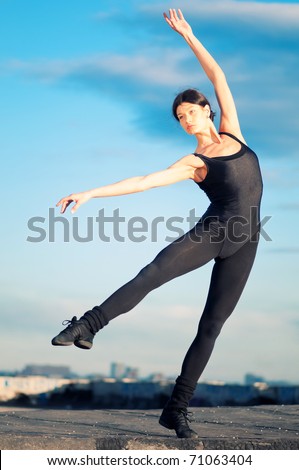 dancing woman in modern pilates style over urban city landscape and blue sky. Yoga