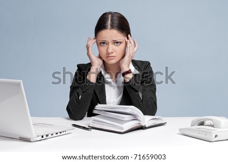 Sad business woman in office working with white table, laptop and diary personal organizer. Headache!