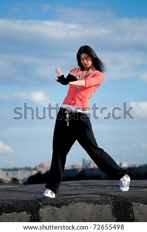 Beautiful woman dancing hip-hop modern style over urban city landscape and blue sky