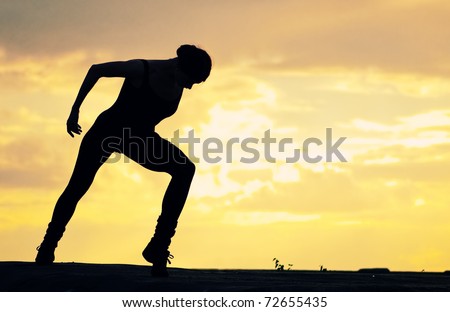 Silhouette photo of dancing woman in modern pilates style over sunset landscape. Yoga