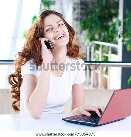 A young attractive business woman sitting in a cafe with a laptop and cell phone