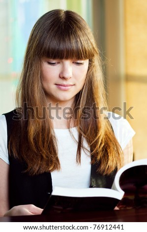 A young attractive woman sitting in a cafe. Reading book