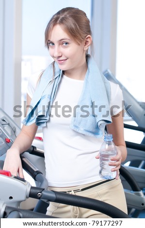 Young woman at the gym exercising. Run on on a machine and drink water