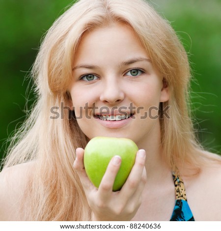 Portrait of a young beautiful woman with green apple at park