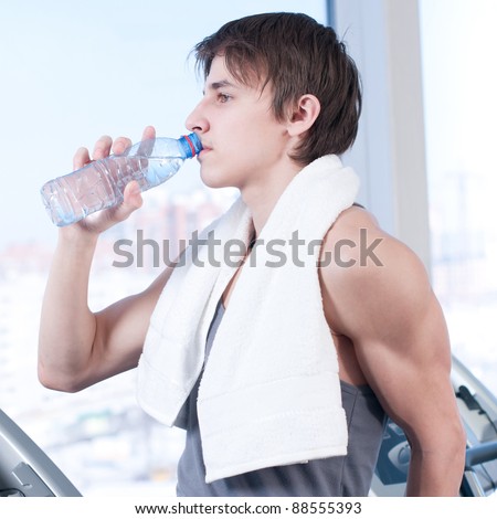 Little break. Handsome young men in sportswear holding water bottle and  looking at camera with smile while sitting at gym 13556699 Stock Photo at  Vecteezy