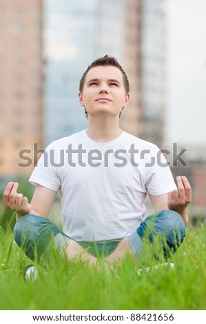 A young man doing yoga at green city park