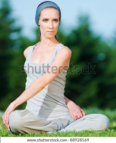 Beautiful woman doing stretching exercise on green grass at park. Yoga