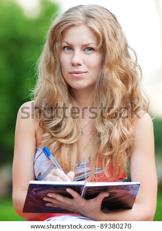 Beautiful young woman study at green summer park