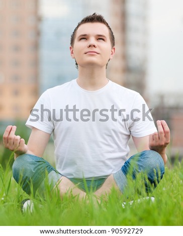 A young man doing yoga at green city park