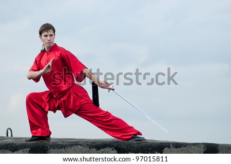 Shaolin warriors wushoo man in red with sword practice martial art outdoor. Kung fu