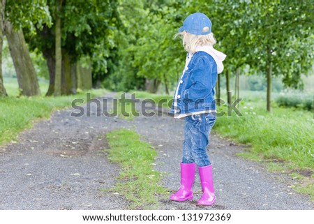 little girl wearing rubber boots in spring alley