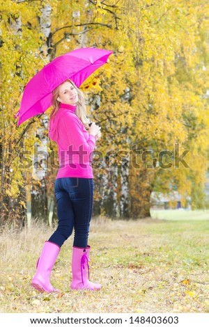 woman wearing rubber boots with umbrella in autumnal nature