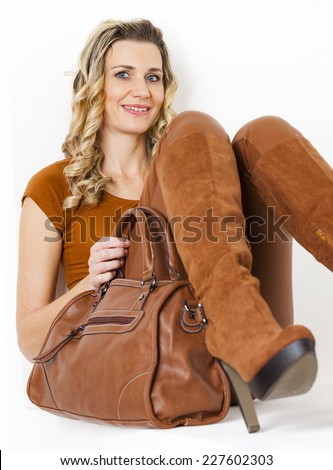 portrait of sitting woman wearing brown clothes and boots with a handbag