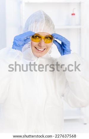 young woman with protective glasses and coat in laboratory