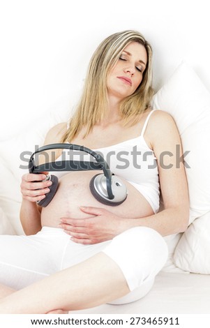 pregnant woman with headphones resting in bed