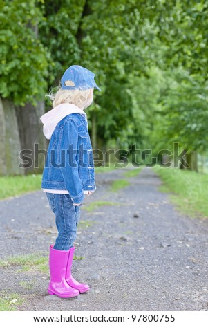 little girl wearing rubber boots in spring alley