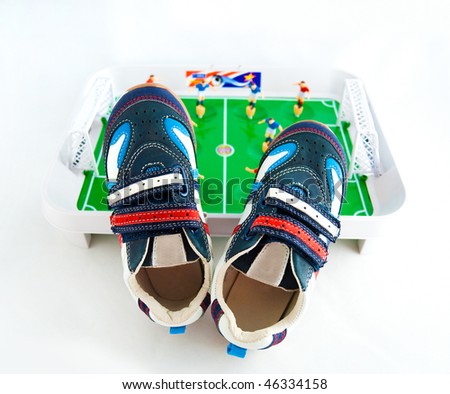 Children\'s sports footwear against a toy football ground