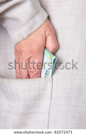 the hand of elderly woman taking away money in a pocket