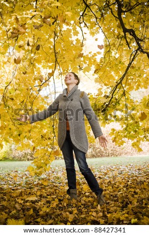 A young woman in the park in fall, relaxing and enjoying the sun.