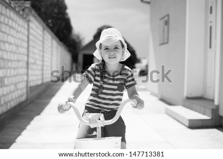 Little girl riding a bike. Retro, black and white.