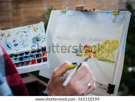 Watercolor painting with brush at the easel 