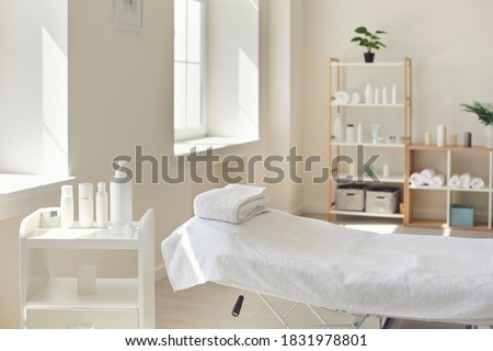 Beauty and body care. Interior of new beauty salon with spa massage table and set of skincare products ready for use. Empty professional dermatologist room waiting for customers