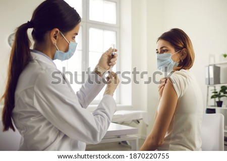 Vaccination and immunization concept. Hospital nurse drawing medication out of vial before giving injection to patient. Young woman getting Covid-19 or flu antiviral vaccine at the doctor's office