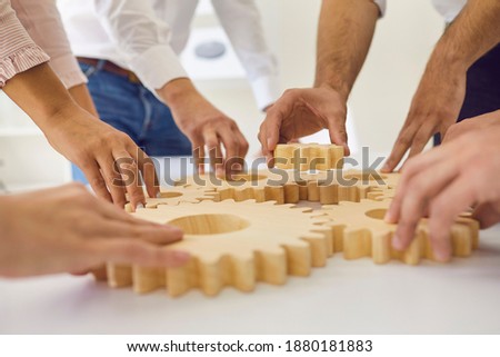Hands of people office workers business partners making common picture of wooden gears on table, selective focus. Teamwork, launching project, corporate business tasks and togetherness concept Foto stock © 