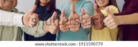 Close up of group of diverse people showing raised thumbs at camera as gesture of recommendation or good choice. Professional multicultural team demonstrates satisfaction and gives a positive response 商業照片 © 