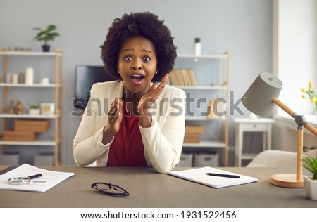 Webcam portrait of cheerful young businesswoman looking at camera with surprised face expression. Happy excited black woman gasps and says Wow in amazement sitting at desk in her office Stock foto © 