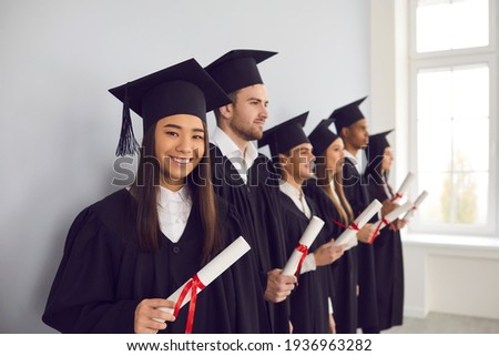 Smiling asian girl student university graduate and classmates standing with diplomas in hands and celebrating in university classroom. Successful graduation from university, education concept