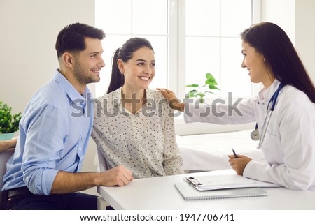 Female doctor consulting young couple patients in fertility clinic about IVF or IUI. Doctor encourages and assures the young couple that everything will be fine. Concept of artificial insemination.