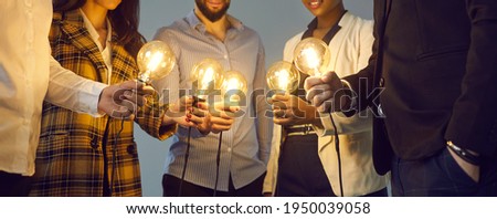 Background with young multiethnic business team holding glowing vintage Edison lightbulbs. Multiracial men and women join shining electric light bulbs as metaphor for teamwork and sharing creative Photo stock © 