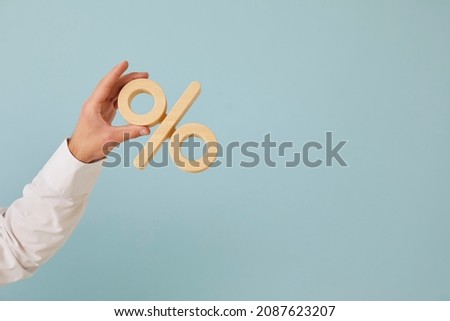 Human hand holding percent symbol. Entrepreneur or client holding percentage sign on blank blue color text copyspace background. Business, finance, mortgage rates, value added tax, or discount concept Stock foto © 