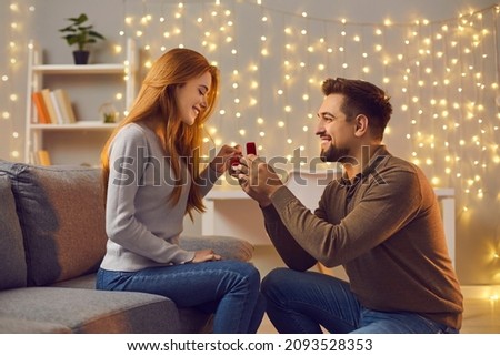 Will you marry me. Couple making love promise to each other on cozy evening at home. Happy woman getting romantic marriage proposal. Young man proposing to girlfriend and giving her engagement ring Foto d'archivio © 