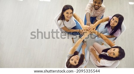 Banner with overhead group portrait of happy positive smiley beautiful young women sitting together, holding hands and looking up. Unity, community helping each other, team aiming for one goal concept 商業照片 © 