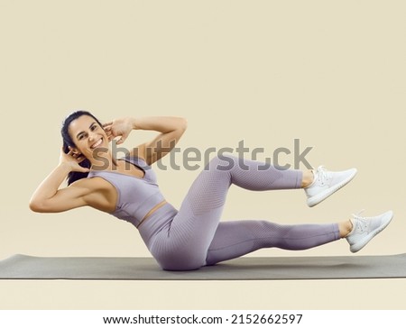 Happy fit woman with beautiful abs enjoying her fitness workout at the gym. Studio shot of a cheerful smiling lady in a crop top and leggings doing bicycle crunches exercise on a sports mat Сток-фото © 
