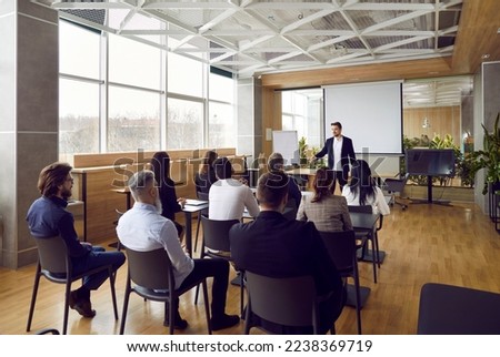 Team of people having class with business trainer. Group of male and female employees sitting at desks in modern office and listening to lecture by experienced teacher sharing knowledge and guidance Zdjęcia stock © 