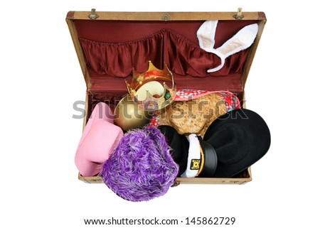Old Vintage Suitcase Isolated on a white background, filled with funny hats and head wear. 1930\'s era suitcase with colorful hats and head wear from various parts of the world and styles. stock photo
