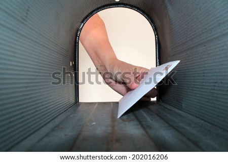 A Unique view of someone getting or placing mail in a mail box, shot from the Inside Out.