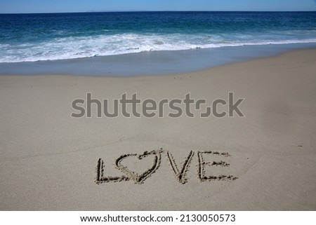 Words written in beach sand. The word LOVE written in the sand on the beach with the ocean as the background. Love is all you need. Everyone Loves the beach. Love.