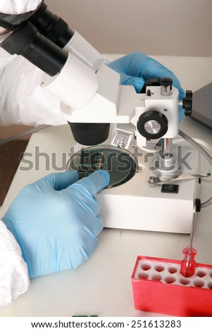 A Professional Computer Forensics Technician examines Computer Micro Chips under his microscope for microscopic damage and for information recovery of important and secret documents for clients.