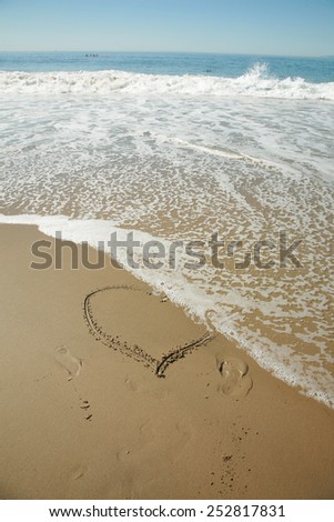 A heart drawing in the sand in Laguna Beach California. The ocean waves gently wash away part of the heart with its gentle action of the ever present tide. Romance is alive and love is here to stay.