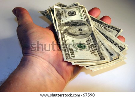 cold hard cash piled high and being held in the hand of a real human being against a white background
