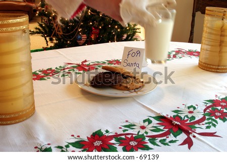 santa claus grabs a glass of mild kindly left for him with a plate of cookies as a snack and thank you on xmas eve
