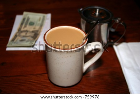Coffee with cream the bill and twenty dollars on a table in a restaurant