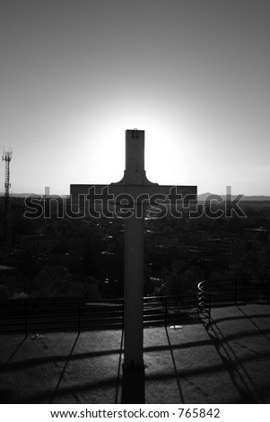 old cross with sunset in background in black and white