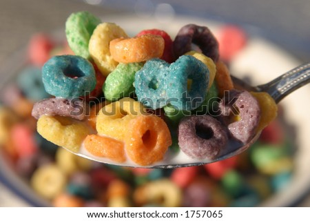 a spoon full of colorful cereal rings in milk